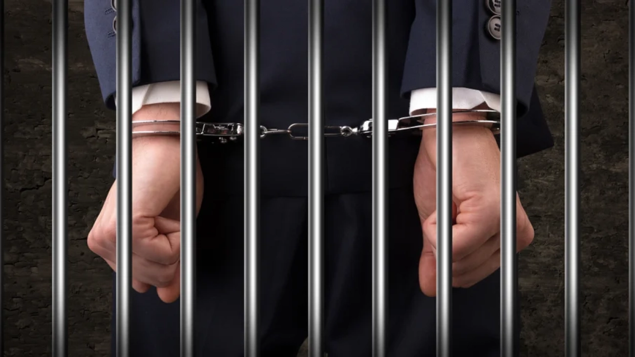 Close convicted man with handcuffs behind grids